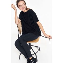 BLUZKA DAMSKA ZE ŚCIĄGNIĘCIEM Z BOKU. Czarne bluzki TROLL, m, bez wzorów, z dzianiny, bez kołnierzyka, bez ramiączek. W wyprzedaży za 29.99 zł.