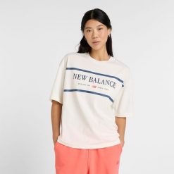 Koszulka damska New Balance WT51910SST – beżowa. Brązowe bluzki New Balance, l, bez wzorów, z bawełny, klasyczne, bez kołnierzyka, bez ramiączek. Za 109.99 zł.