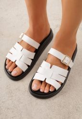 Białe Klapki z Przeplatanymi Paskami i Klamrą Ravelya. Białe klapki Born2be, bez wzorów, z jeansu, bez obcasa, na płaskiej podeszwie. Za 79.99 zł.