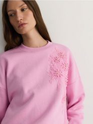 Bawełniana bluza z aplikacją - pastelowy róż. Czerwone bluzy Reserved, l, z aplikacjami, z bawełny, bez kaptura. W wyprzedaży za 69.99 zł.