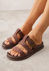 Brązowe Klapki Ozdobione Geometrycznymi Paskami i Metaliczną Klamrą Hossei. Brązowe klapki Renee, bez wzorów, bez obcasa, na płaskiej podeszwie. Za 69.99 zł.