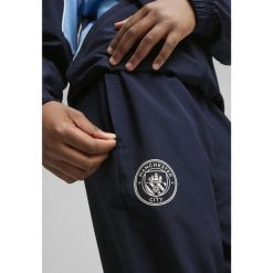 Młodzieżowe spodnie Manchester City ftblARCHIVE PUMA Navy Team Light Blue. Niebieskia spodnie dresowe Puma, m, bez wzorów, z dresówki, do piłki nożnej. W wyprzedaży za 189.00 zł.