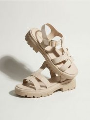 Sandały z imitacji skóry na platformie - kremowy. Białe sandały Sinsay, bez wzorów, ze skóry, bez obcasa, na platformie, bez zapięcia. Za 49.99 zł.