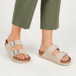 Klapki Damskie Rieker, cholewka skóra naturalna gładka dwa szerokie paski z metalowymi klamrami odkryte palce regulowane zapięcie. Szare klapki Rieker, bez wzorów, ze skóry, bez obcasa. Za 299.00 zł.