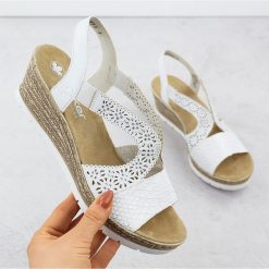 Białe sandały damskie Rieker ażurowy wzór. Białe sandały w ażurowe wzory, ze skóry ekologicznej, eleganckie, bez obcasa, na koturnie, bez zapięcia. Za 483.82 zł.