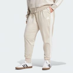 Spodnie Dresowe Essentials 3-Stripes (Dla Sylwetek Plus Size). Białe spodnie dresowe Adidas, plus size, bez wzorów, z dresówki, na fitness i siłownię. Za 219.00 zł.
