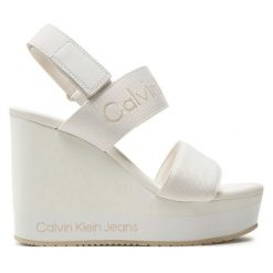 Sandały Calvin Klein Jeans. Białe sandały Calvin Klein Jeans, bez wzorów, z jeansu, bez obcasa, na koturnie, bez zapięcia. Za 319.99 zł.