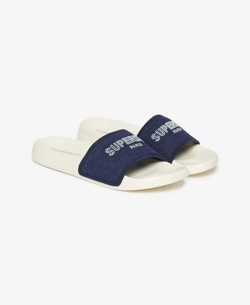 Superdry Klapki Rhinestone Luxe Pool Slide z EVA – OFF WHITE. Białe klapki Superdry, z aplikacjami, z materiału, bez obcasa. Za 147.05 zł.