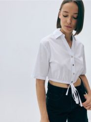 Krótka koszula z wiązaniem - złamana biel. Koszule Reserved, l, bez wzorów, z bawełny, bez kołnierzyka, bez ramiączek. W wyprzedaży za 29.99 zł.